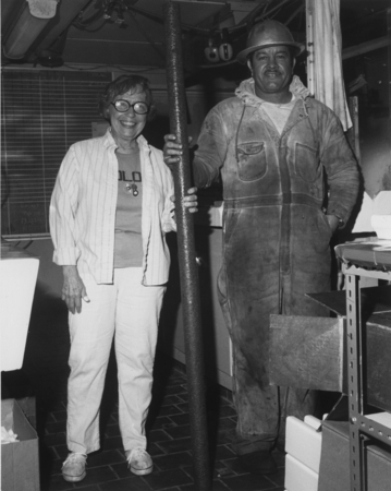 Geologist Doris Curtis (left) helps a roughneck hold a column of continuous cored basalt two meters tall from Site 445 on ...
