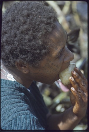 Western Highlands: woman with facial tattoo, eating yam