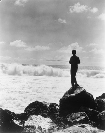 Boy standing on rock surf fishing