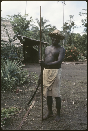 Portrait of man holding long rod and machete