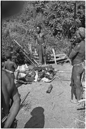 Distribution of wild pig meat: men discuss distribution of cooked pork