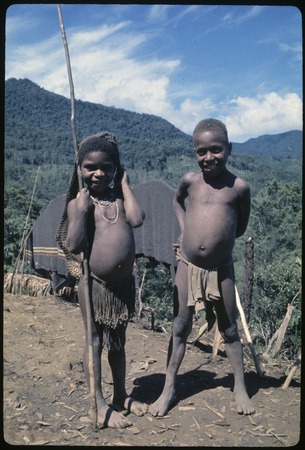 Children, Pauna (l) on her way to garden with stick and net bag, and Kobenum (r)