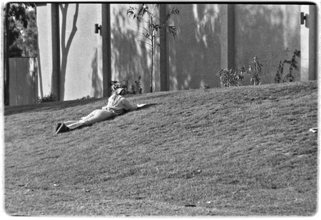 Student laying on grass, near the Recreational Gym