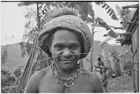 Young man wears adornments, including barkcloth cap and trade-bead necklace