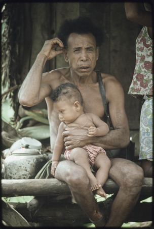Mowaroka&#39;s father, tattoo on left arm, holds a baby