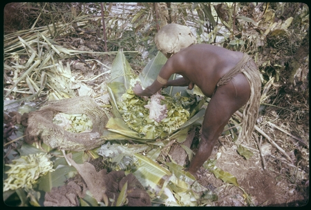 Pig festival, pig sacrifice, Torpai: Koi places pig intestines over greens on banana leaves