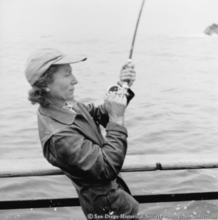 Woman on sportfishing boat reeling in fish