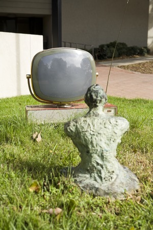 Something Pacific: bronze Buddha contemplating old tv monitor on grassy mound near UCSD Media Center