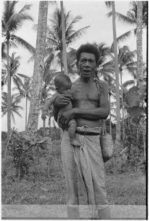Man holds infant, basket hangs from man&#39;s shoulder
