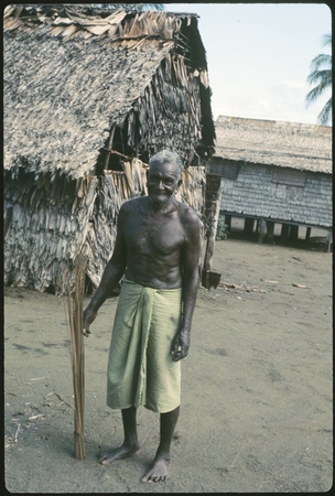 Portrait of man. Village dwellings in back
