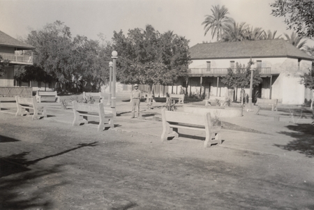 [Man standing in park at center of village]