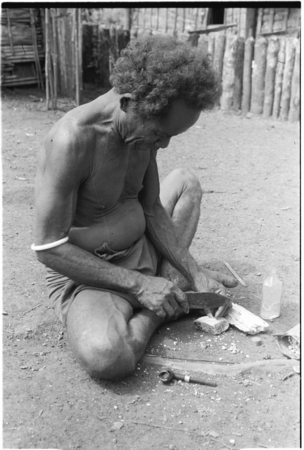 &#39;Iika chipping edges off of coneshells with a knife, one step in making kofu shell money beads, at Fanuaba&#39;ita.