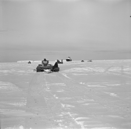 Tractors and sledges on the sea ice going to the research ship Ob to unload supplies and equipment