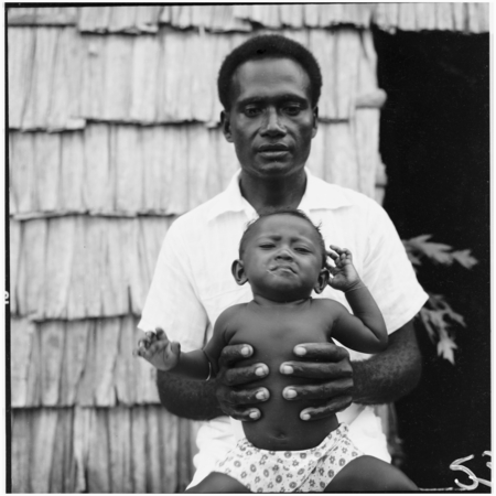Man and infant in front of house