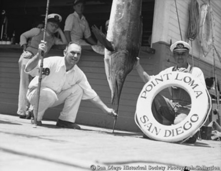 Man with fishing rod posing with marlin catch
