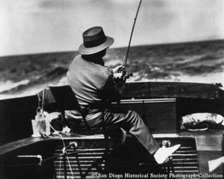 Man on swivel seat fishing from stern of boat