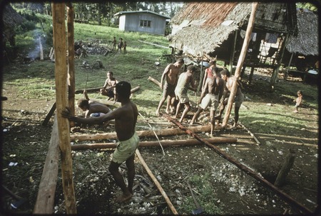 House-building: men build frame for a new house, putting in vertical supports