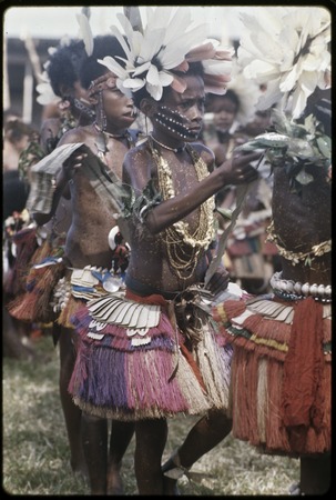 Dance: children wear short grass skirts, shell necklaces, and feathers, carry flattened pandanus leaves
