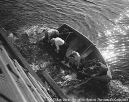 Tuna fishermen on small boat pulling in net
