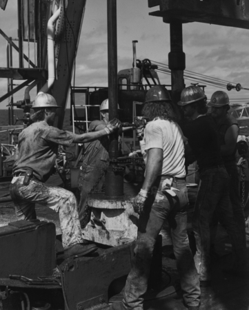 Roughnecks guide the drill string into position during Leg 68 of the Deep Sea Drilling Project. Action took place on the r...