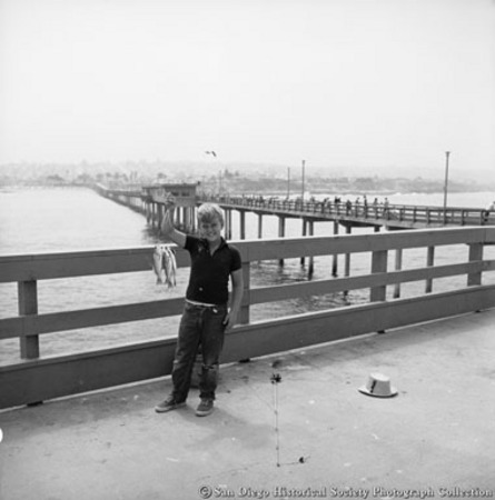 Boy holding up fish caught from pier at Ocean Beach