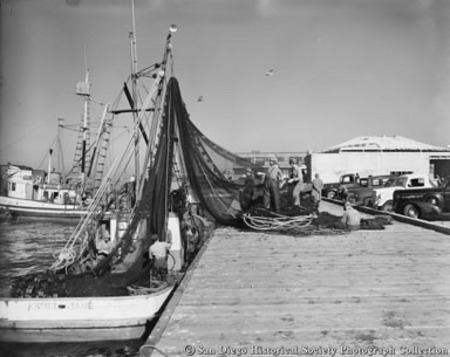 Fishermen tending nets by docked fishing boat Kathie Jane