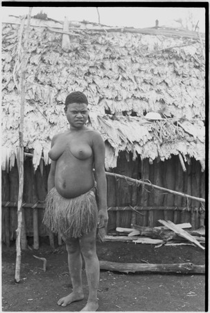 Yeria, Wanuma Census Division: woman in grass skirt stands in front of house