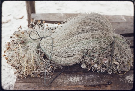 Fishing net with shell weights and floats cut from old rubber sandals
