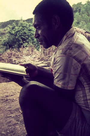 Missionary&#39;s trainee reading the New Testament in Pidgin English (Tok Pisin)