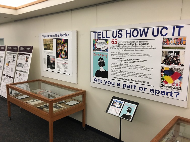 a picture of the exhibit area include canvas panels on the wall featuring items from the archive, display cases highlighting the brown vs board of education court case, and campus timeline banners