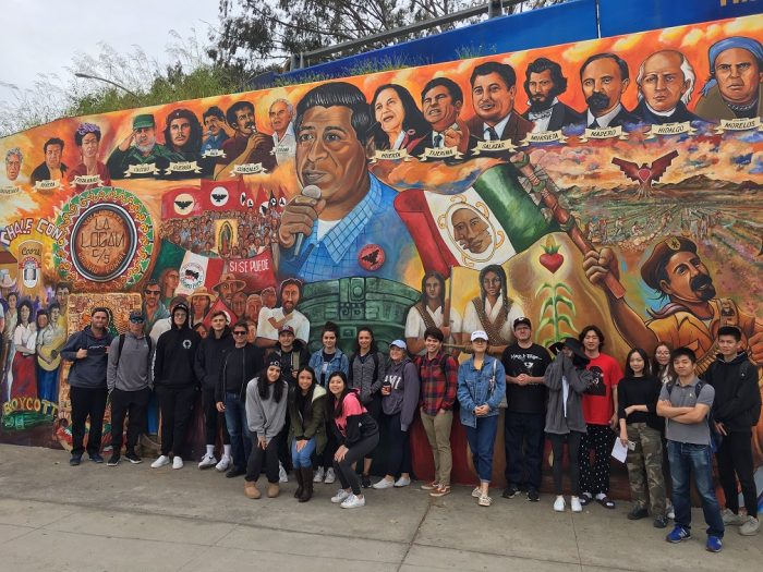group picture of class in front of mural at Chicano Park, San Diego