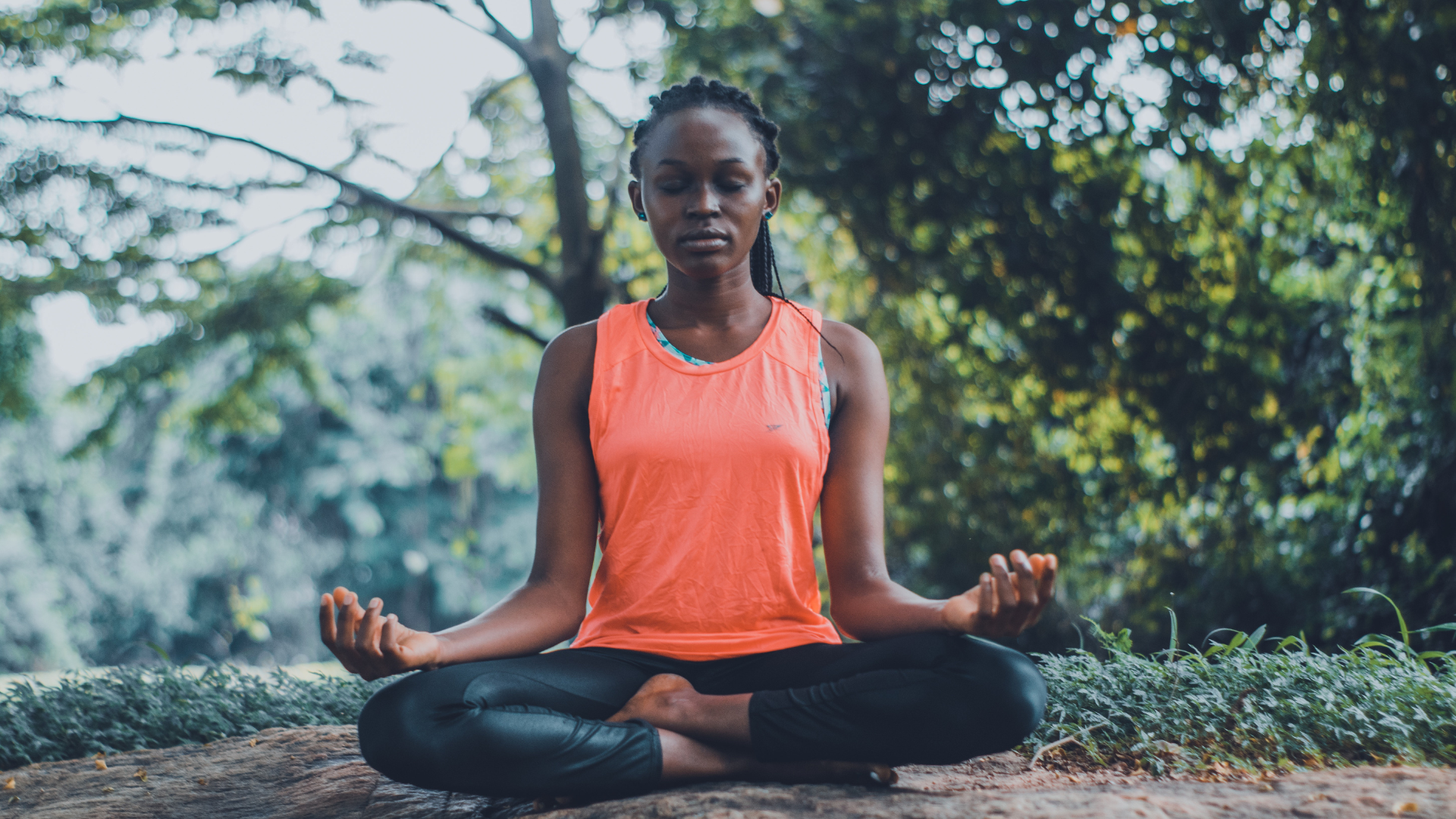 A Black woman in a half lotus yoga pose.