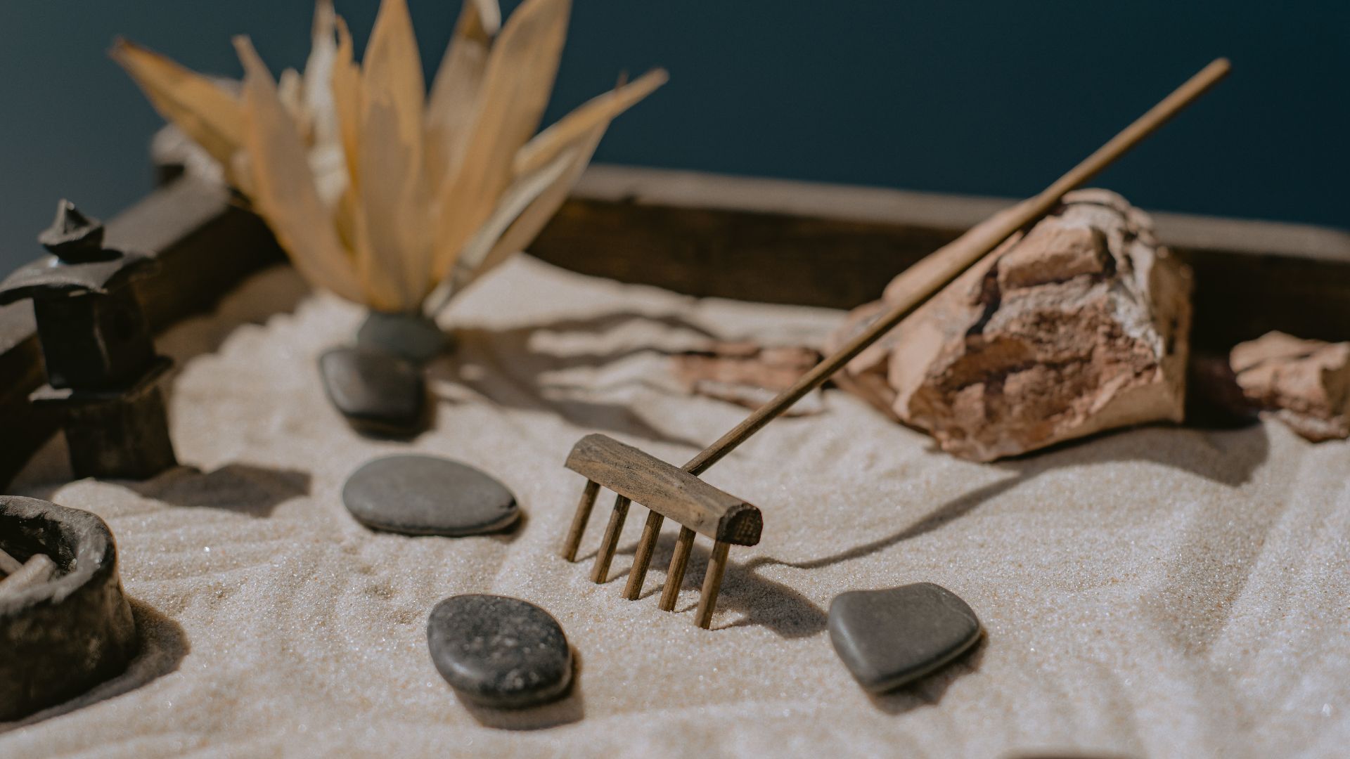 Close-up photo of a Zen garden with sand, rocks and a rake.