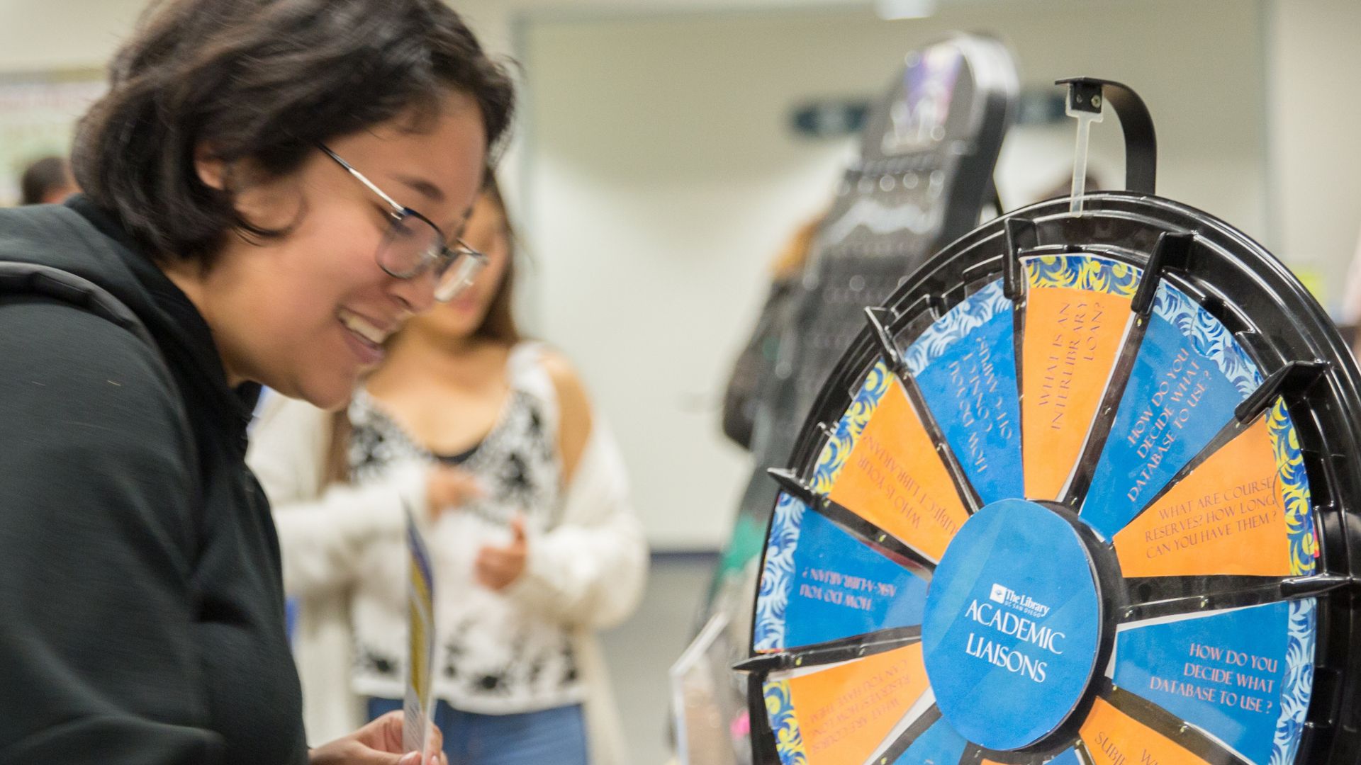 A student at Geisel Library engaging with a spinning wheel to win a prize.